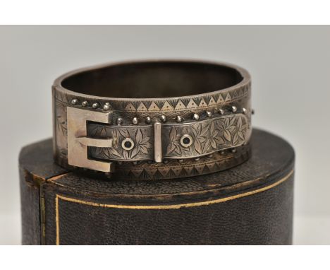 A LATE VICTORIAN SILVER HINGED BANGLE, of a belt and buckle design, floral detail with applied bead work surround, push butto