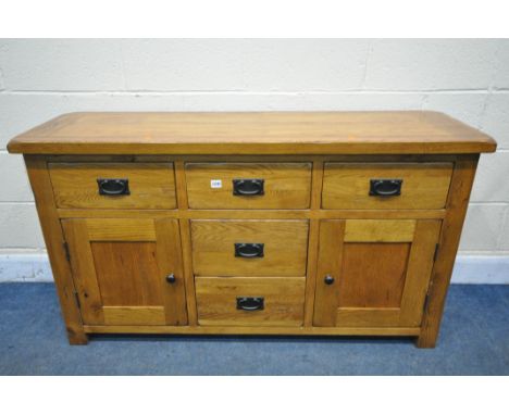A GOLDEN SOLID OAK SIDEBOARD, with five drawers, and panelled cupboard doors, width 139cm x depth 43cm x height 77cm (conditi