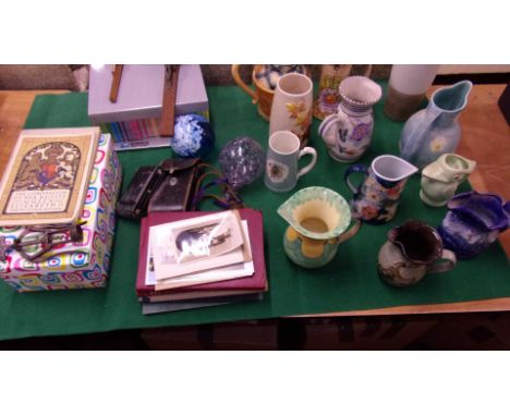 collection of ceramic jugs. 2 glass orbs, Royal memorabilia, a camera, boxes of postcards and other miscellaneous items.&nbsp