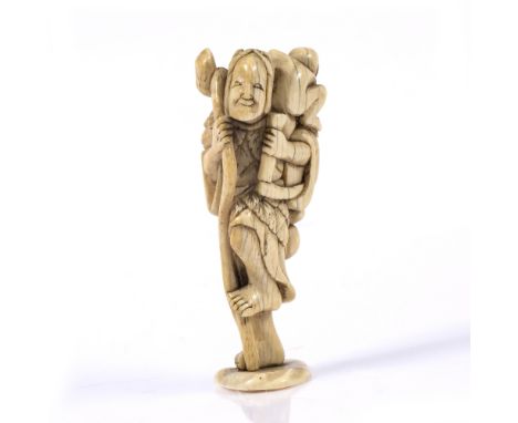 Ivory netsuke Japanese, Kyoto 18th Century a standing sennin holding a staff and hand scythe while supporting an infant on hi