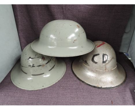 Three British Steel Helmets, first silver helmet has painted CD and Lighning Bolt with leather liner marked TTC 1941 size 7, 