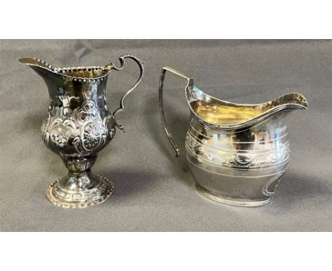 GEORGIAN STERLING SILVER CREAM JUGS both of helmet form, one standing 10.5cm tall, decorated with embossed floral and ribbon 