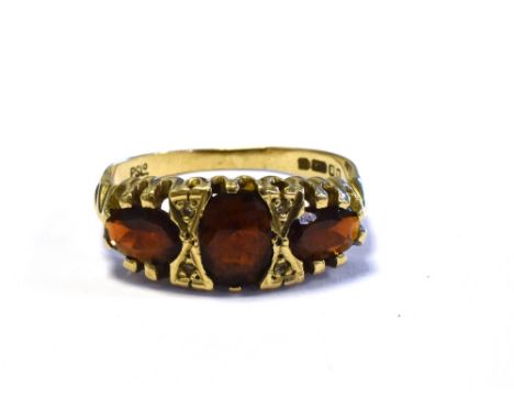 GARNET &amp; DIAMOND TRILOGY RING mounted in 9ct gold and set with three oval cut pyrope garnets and single cut diamonds, rin