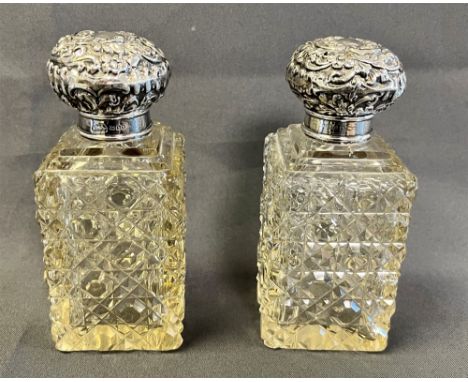 A PAIR OF EDWARDIAN SCENT BOTTLES standing 14.3cm tall, hob nail cut crystal bases, complete with original faceted stoppers a
