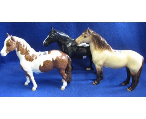 Group of three Beswick china horses, black standing hunter, palomino Highland pony and a skewbald pony, printed marks. (3)(B.