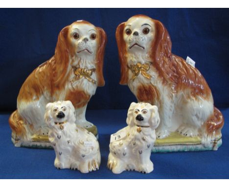 Pair of late Staffordshire Pottery red and white seated King Charles Spaniels with glass eyes and over gilded decoration, 32c