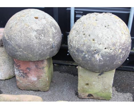 Two 19th century spherical architectural finials, each with a flattened underside upon associated sandstone blocks, 76cm and 