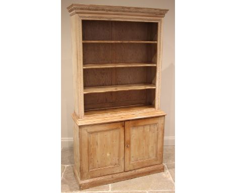 A 19th century limed pine bookcase, the moulded and carved foliate cornice, over three open wavy shaped shelves and a pair of