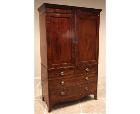 An early 19th century mahogany linen press, the moulded cornice over a pair of flame mahogany doors, outlined with boxwood st