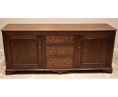 A 19th century oak dresser base, the rectangular top with canted front corners over a central bank of three graduated and coc
