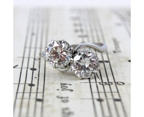 A mid 20th century diamond 'Toi et Moi' ring, the two round cut diamonds within an eight claw white metal setting edge, leadi