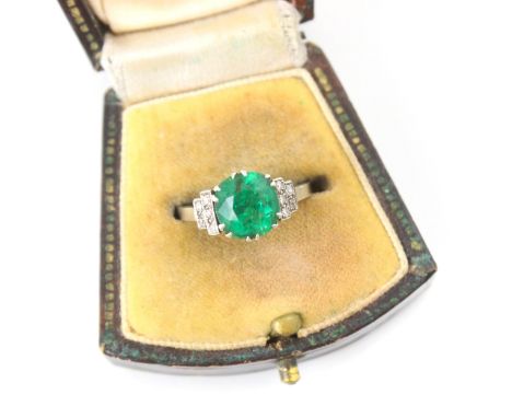 An early 20th century untested emerald and diamond ring, the central cushion cut untested emerald within white metal claw set