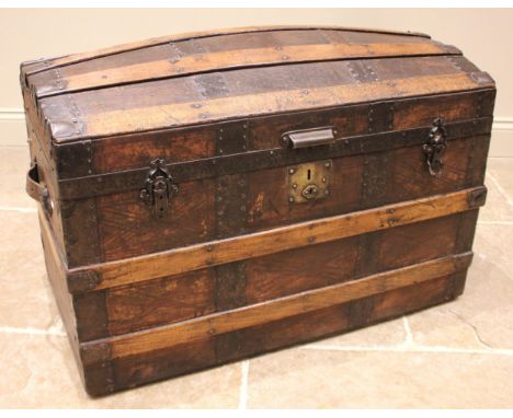 A Victorian leather covered and slatted domed trunk, applied with side leather loop handles and clasp locks, opening to a lin