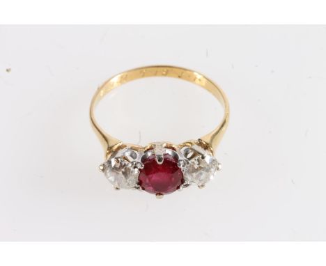 Unmarked yellow metal ruby and diamond three stone ring, the central faceted oval ruby flanked by ~0.4ct round cut diamonds, 