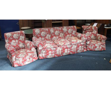 Early 20th century three seat settee with red ground floral patterned covers, and a pair of matching armchairs.  Appears well