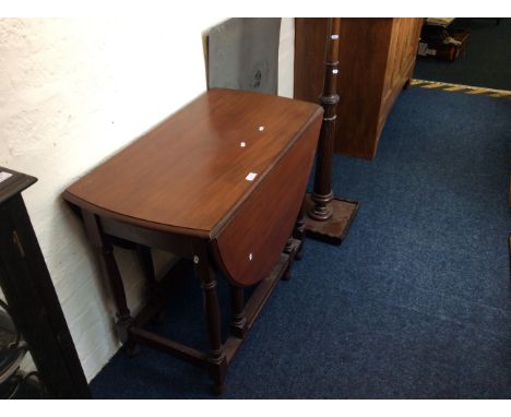 An oak gate leg drop leaf table together with an oak standard lamp.