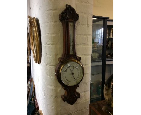 A wall mounted walnut barometer with carved decoration.