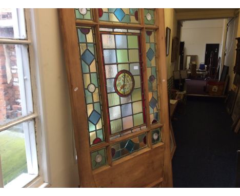 A pine door with multicoloured stained glass panels with bird design centre panel.