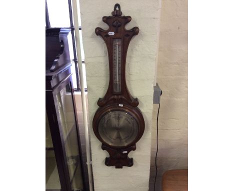 An oak wall mounted barometer with carved decoration.