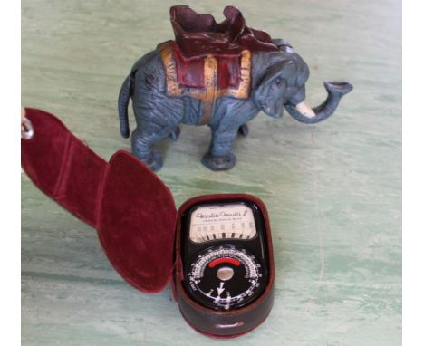 A cast metal elephant money box together with a vintage camera light meter