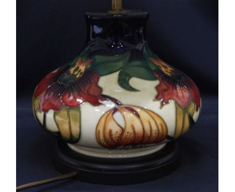 A modern Moorcroft tube lined squat table lamp decorated with flowers on a cream ground, with cream pleated lamp shade