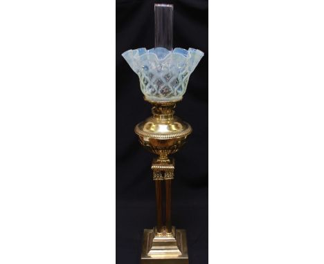 A late 19th -early 20th Century landscaped brass oil lamp with tinted glass shade. Fluted brass front on quadruple reeded col