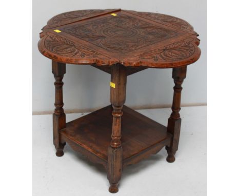 An early 20th century carved oak quatrefoil drop leaf card table, the top ornately carved with acanthus leave and supported o