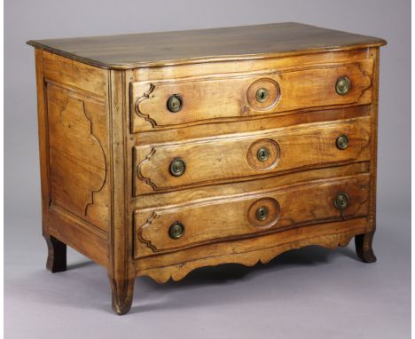 A late 18th/early 19th century French provincial walnut commode of serpentine shape, fitted three long drawers with brass rin