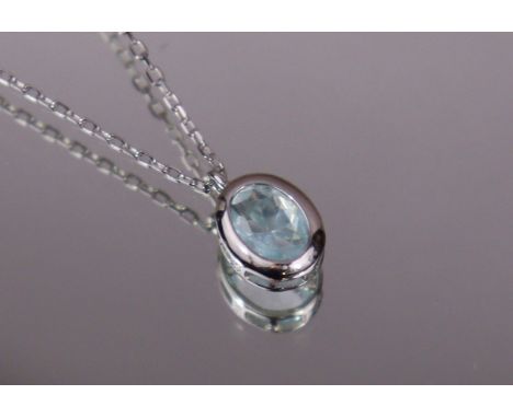 A pale blue topaz pendant, the oval-cut stone set in silver rub-over mount, on silver fine-link chain necklace. (2.2gm).