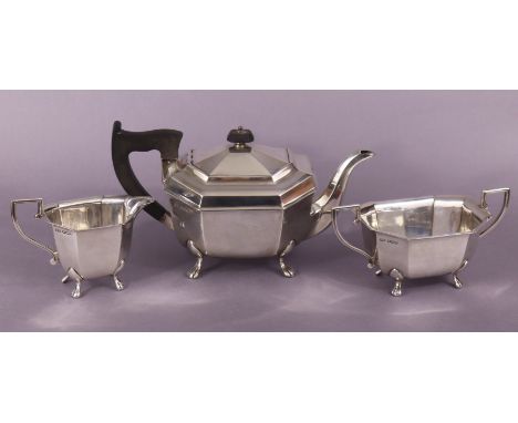 A George VI silver three-piece tea service of eight-sided oblong shape, each on four paw feet; Sheffield 1947, by E. Viner. (