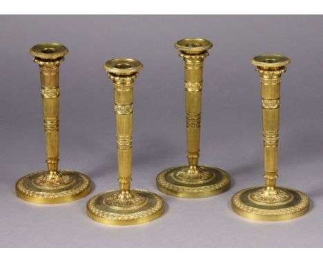 A set of four late 19th/early 20th century gilt-brass candlesticks, in the neoclassical style, with foliate &amp; guilloche m
