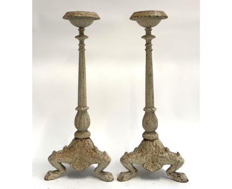 A pair of white painted cast iron candlesticks on tapering columns on a tripod base with foliate detail, each 55cmH 