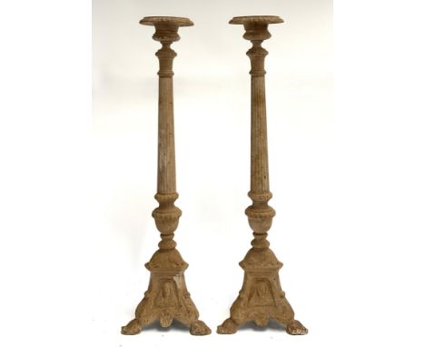 A pair of cast iron candlesticks on tapering columns on a tripod base, each 70.5cmH 