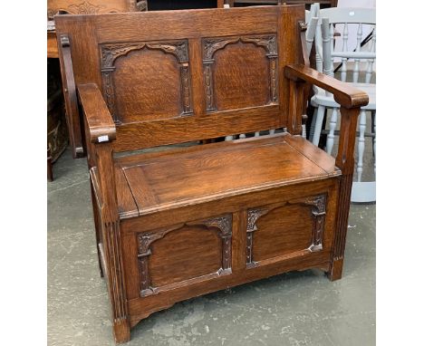 An oak metamorphic monk's bench, with hinged seat, over two carved panels, 91x48x74cmH 