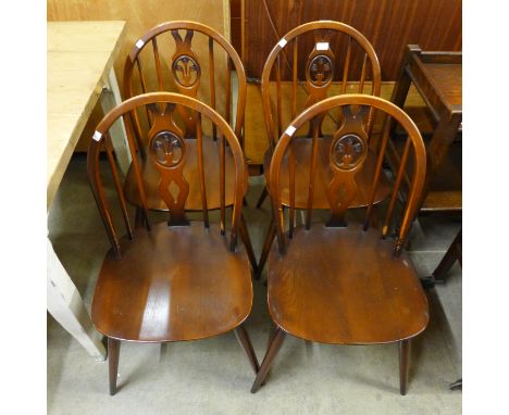 A set of four dark Ercol elm and beech fleur de lys chairs 