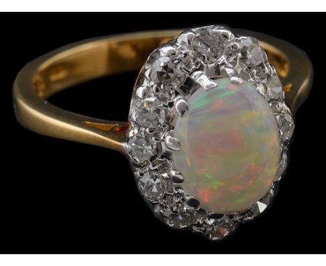 An 18ct diamond and opal ring, the central opal with full vibrant colour and high cabochon form surrounded by 12 diamonds