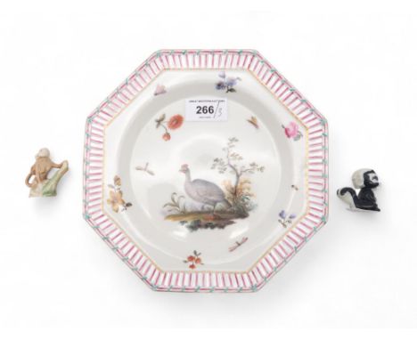 A German porcelain plate, painted with a Guinea Fowl, together with an early Wade monkey group and a figure of a cartoon skun