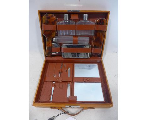A vintage travelling vanity case, with glass bottles, containers, mirror, brushes and nail tools