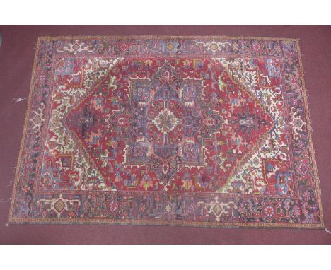 An antique Heriz carpet with geometric medallion on a red ground, contained by geometric borders, 289 x 200cm 