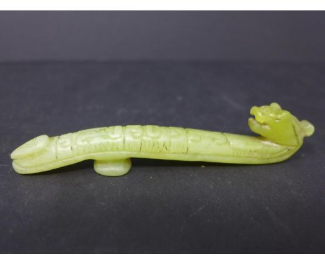A Chinese, hand-carved yellow/green jade rest in the form of a mythical beast, H. 2cm, L. 10cm 