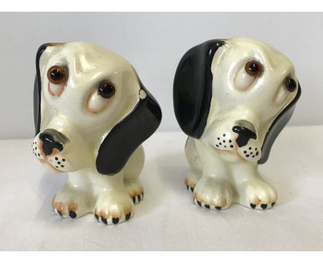 A pair of Crown Devon Fieldings ceramic dog figurines. Cream, black and brown colouration. One eye loose. Approx. 8½ cm tall.