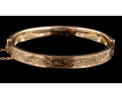 A 9 carat gold hinged bangle: half engraved with a foliate motif, stamped 375 with full Birmingham hallmarks for 1969, 6.1cm 