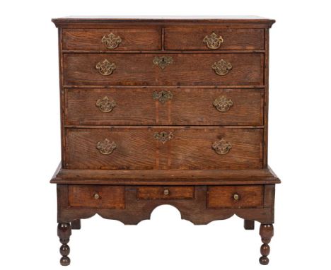 An 18th Century oak and crossbanded chest on a later stand:, the upper part with a moulded top, containing two short and thre