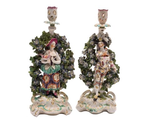 A pair of Derby bocage candlestick figures of the Italian Farmer and Wife: wearing colourful eighteenth century costume, he h
