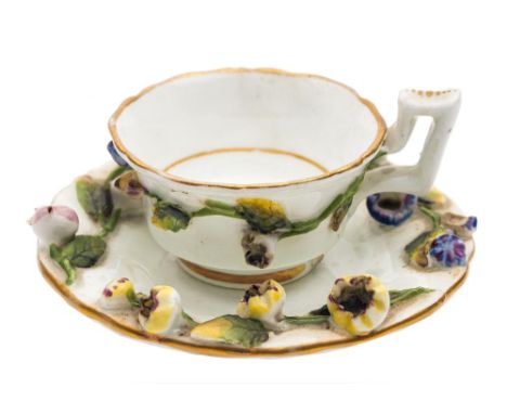 A Rockingham porcelain miniature cup and saucer: applied with leafy floral sprays, puce mark, circa 1830-40, saucer 7cm diame