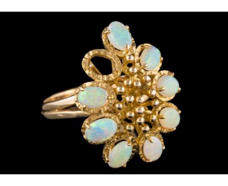 A 14 carat gold opal dress ring: set with oval cabcohon opals surrounding a beaded centre, stamped 585 with London import mar