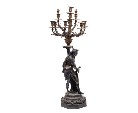 A large Victorian bronzed spelter figural ten light candelabrum:  the ten foliate branches with urn-shaped sconces issuing fr