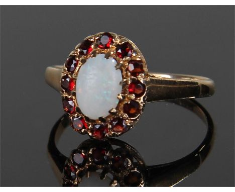 9 carat gold opal ring ring, set with central oval opal, flanked by red stones, ring size M