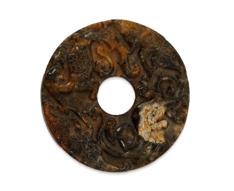 A CHINESE JADE DISC of circular form carved in high relief depicting various animals within scrolls and other motifs, 8.3cm, 