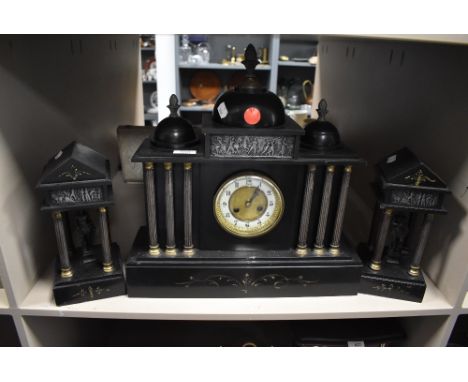 A slate mantel clock with matching garnitures